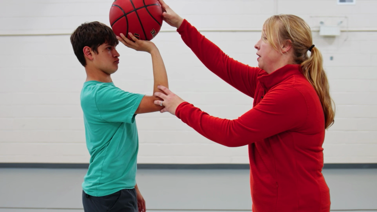 Krista Gingrich-White, Perfec'Shot founder, demonstrating proper shot alignment to young basketball player